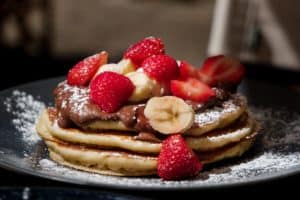 Stack of pancakes with nutella, stawberries and banana